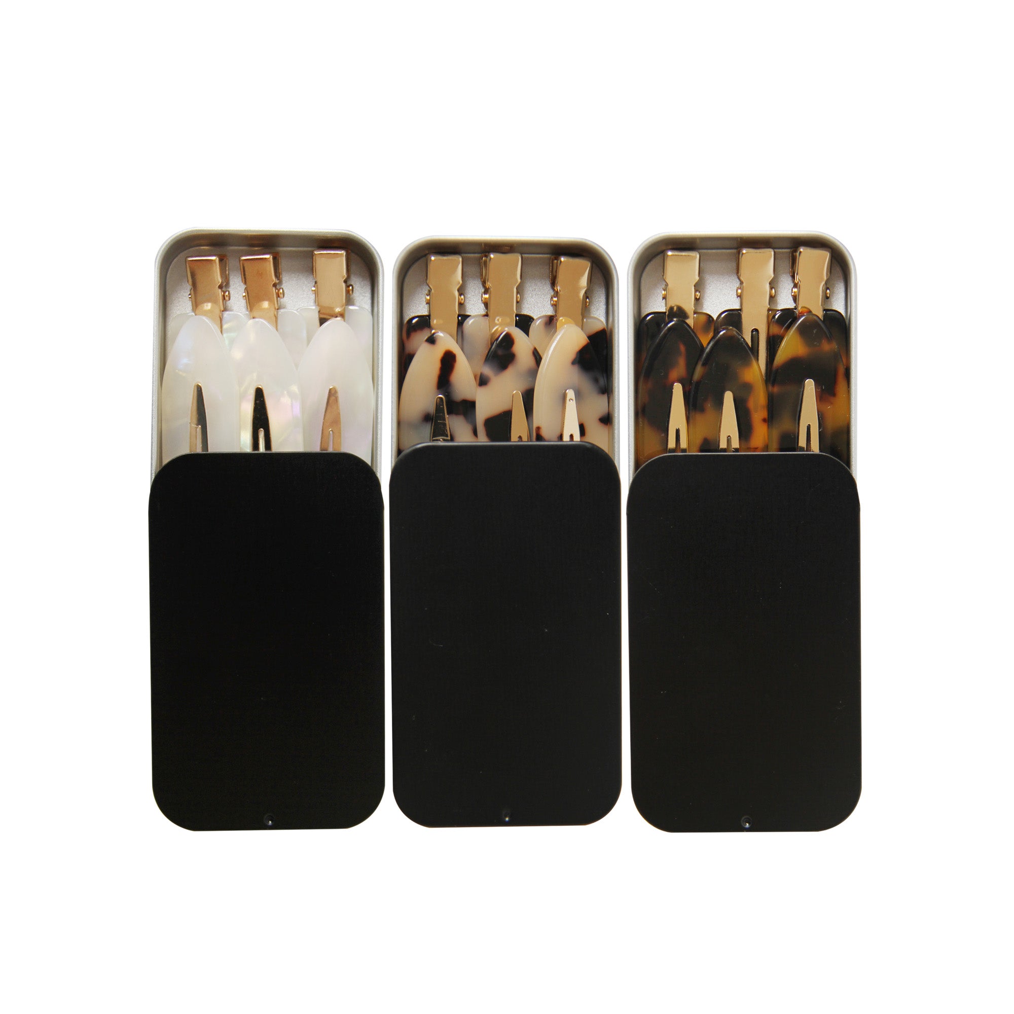 Three black tins each one holding six non crease hair clips on a white background