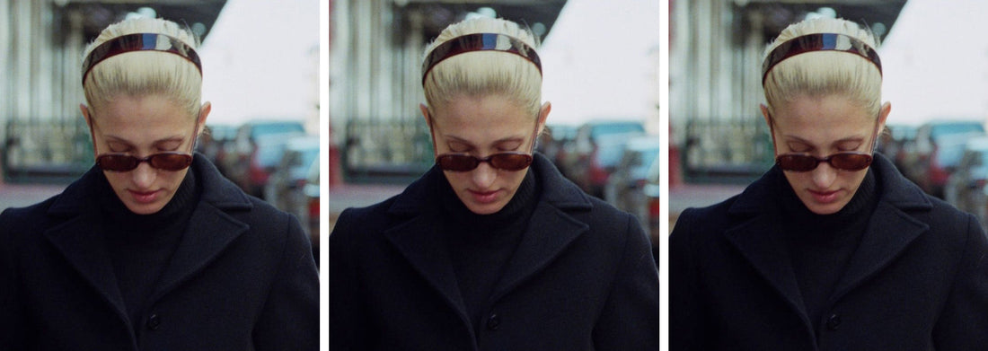 A picture of Carolyn Bassette-Kennedy, with her blonde her pull back and she's wearing a tortoiseshell resin hairband, she's wearing a winter coat and walking in New York
