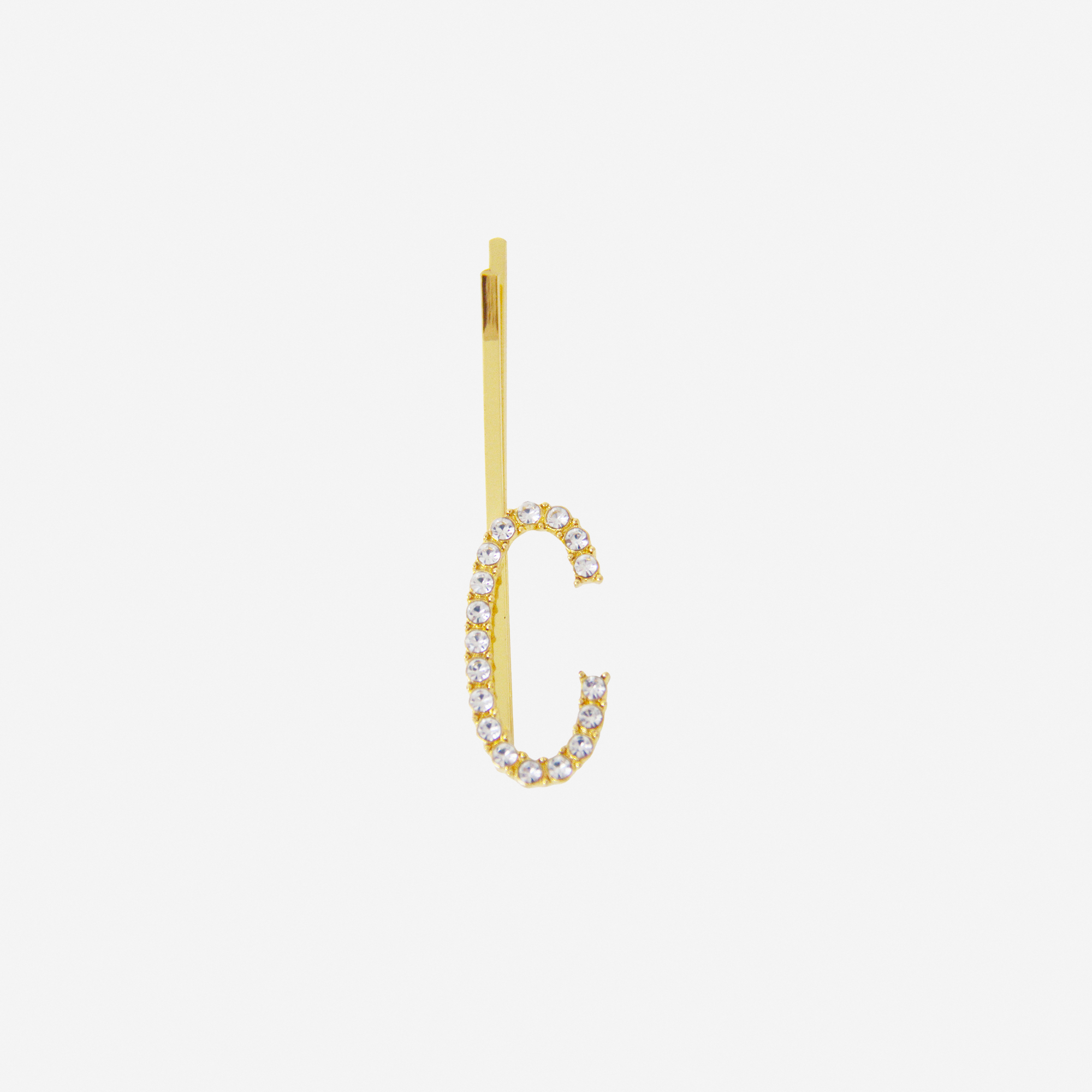 Gold and crystal hair slide featuring the letter 'C' on an off white background