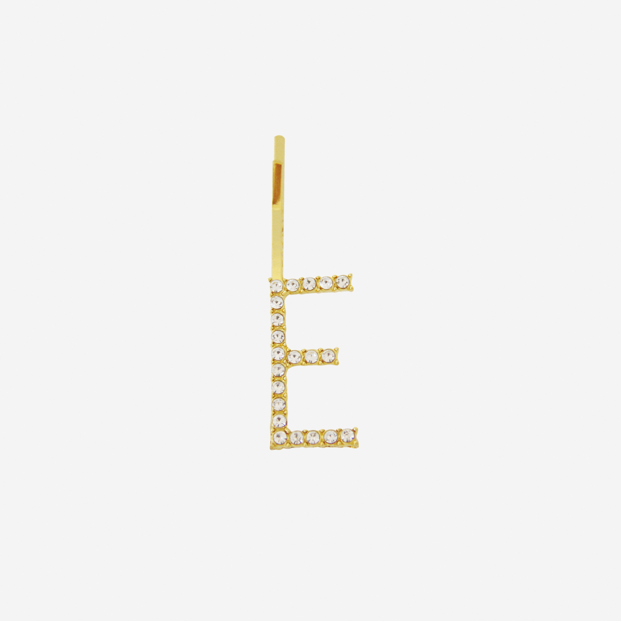 Gold and crystal hair slide featuring the letter 'E' on an off white background