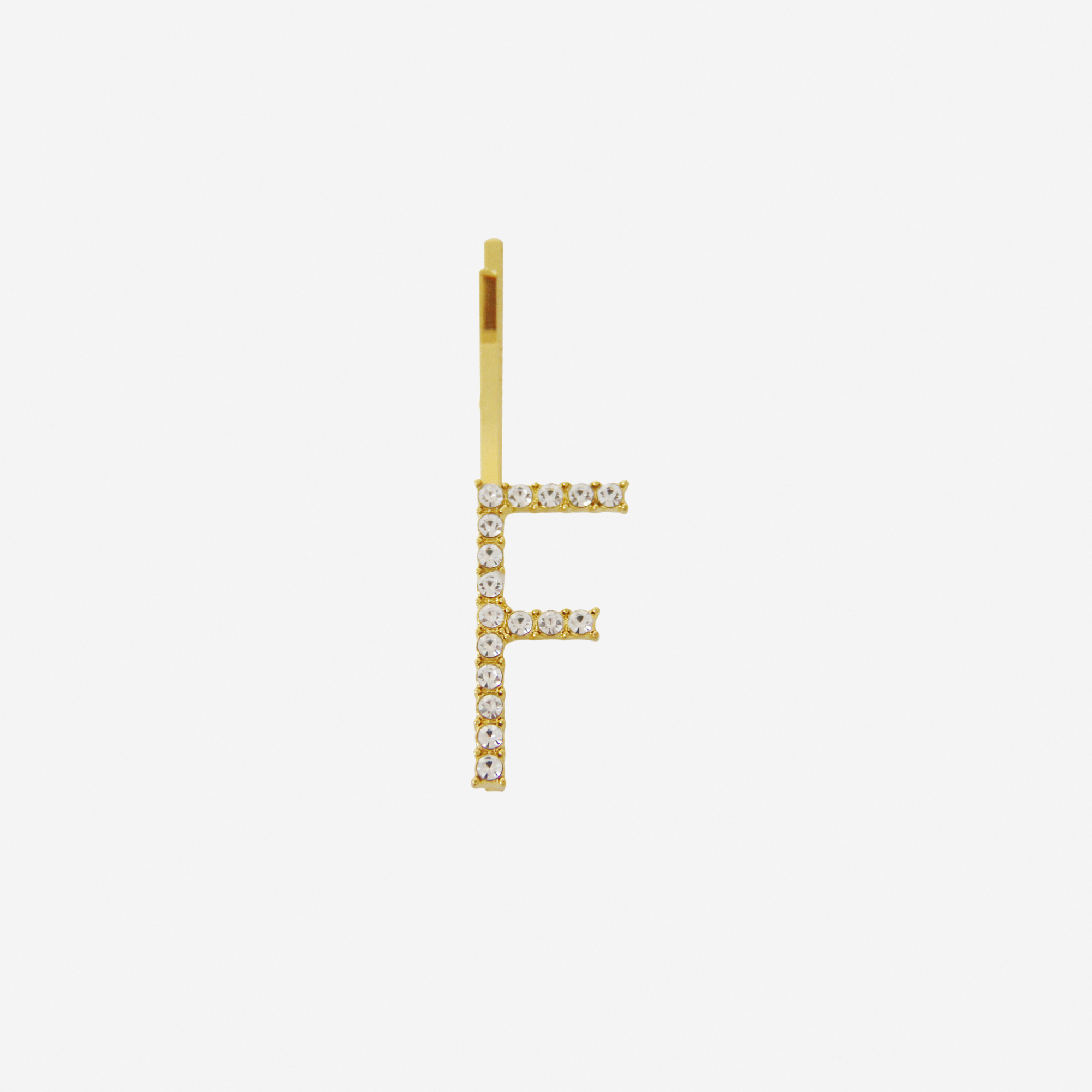 Gold and crystal hair slide featuring the letter 'F' on an off white background