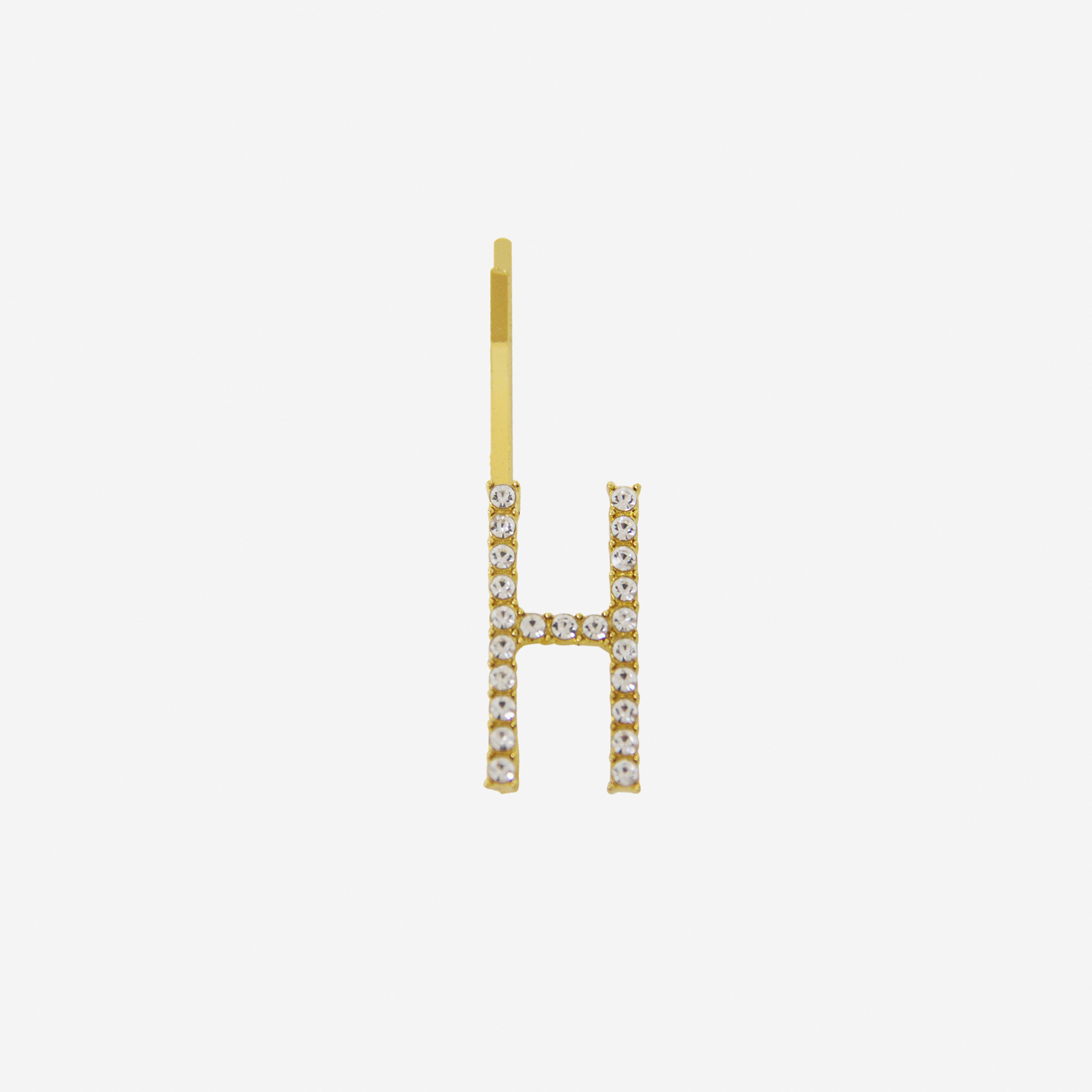Gold and crystal hair slide featuring the letter 'H' on an off white background