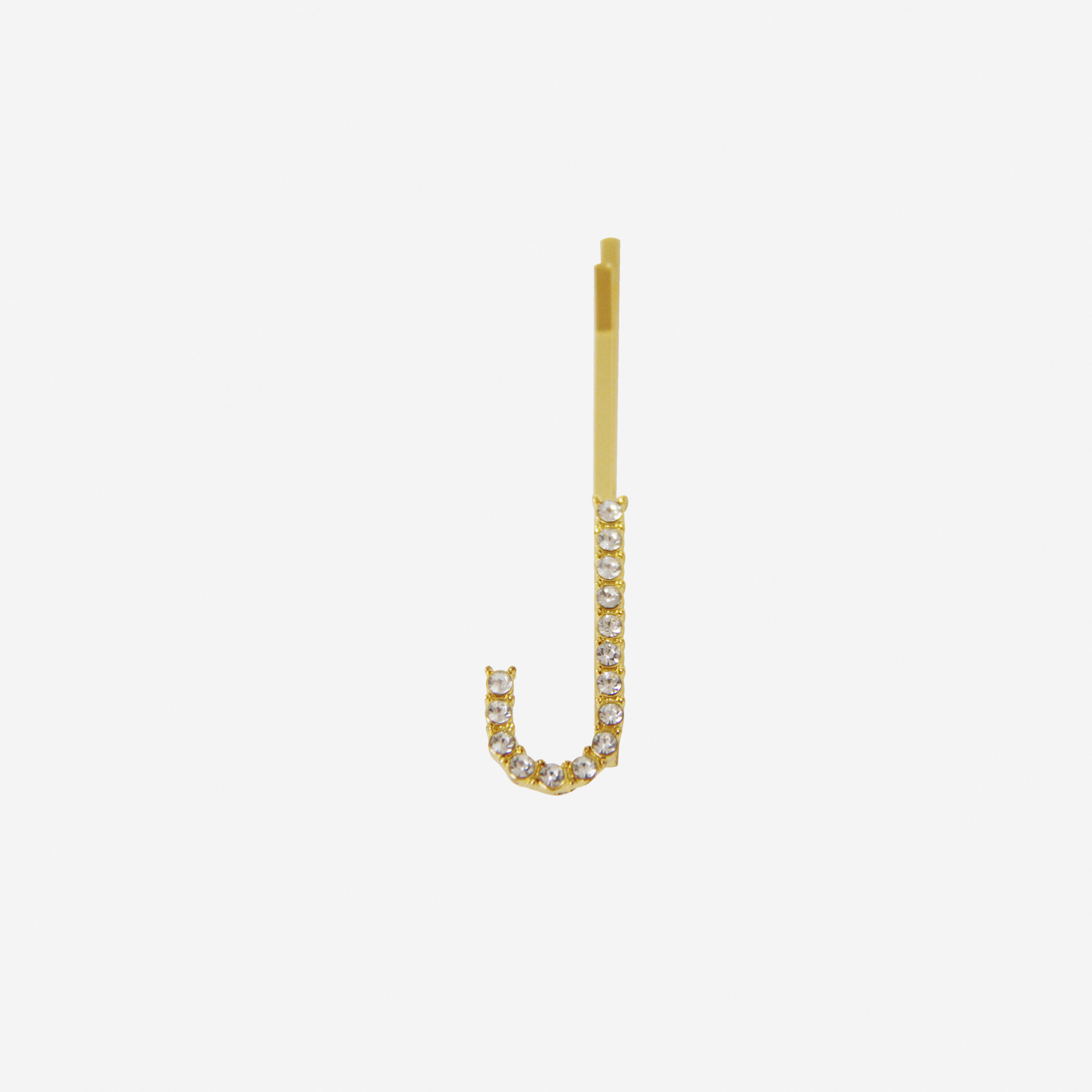Gold and crystal hair slide featuring the letter 'J' on an off white background