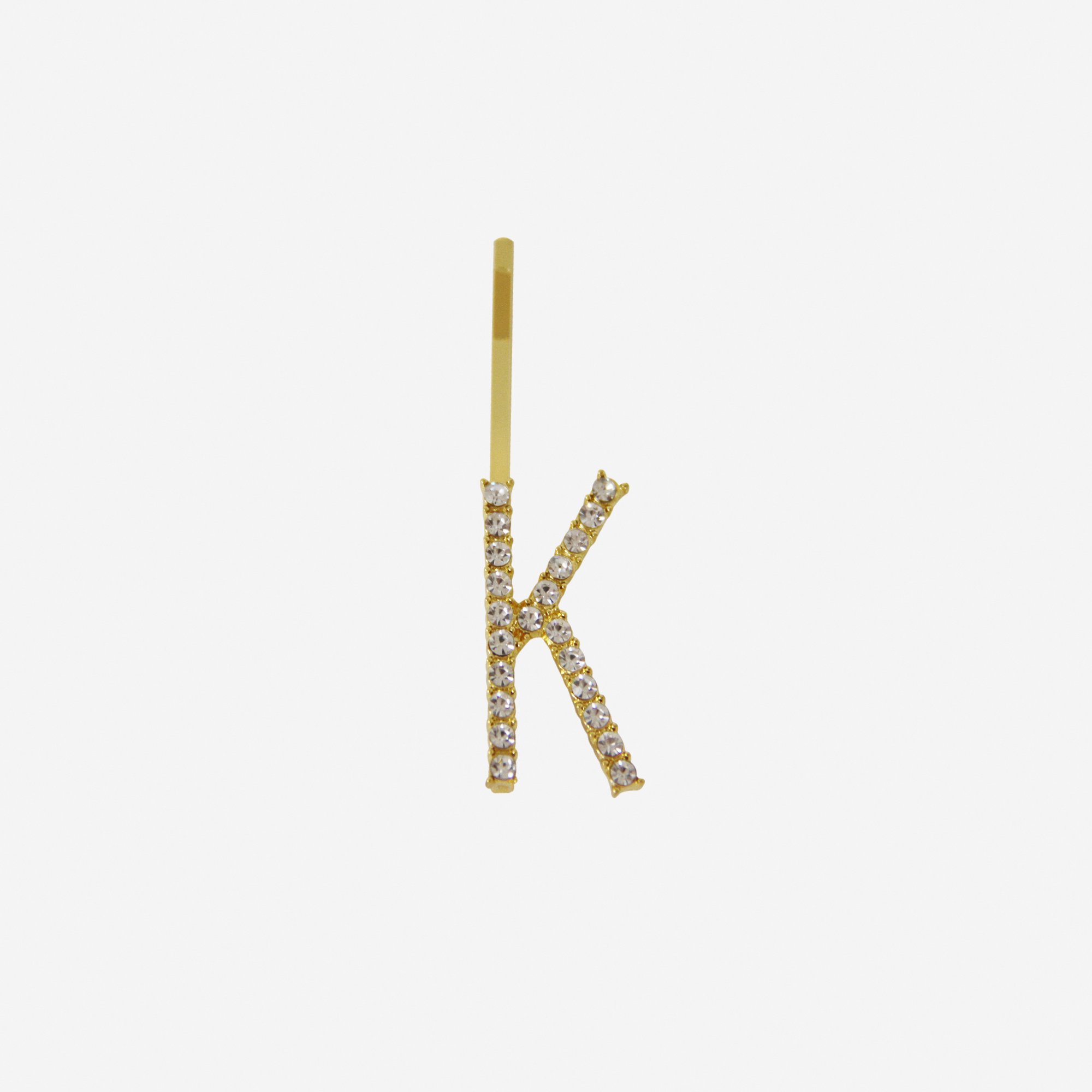 Gold and crystal hair slide featuring the letter 'K' on an off white background