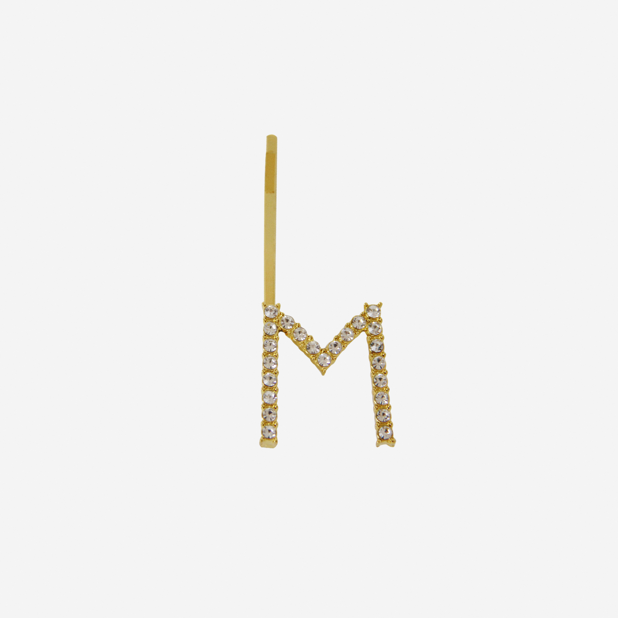 Gold and crystal hair slide featuring the letter 'M' on an off white background