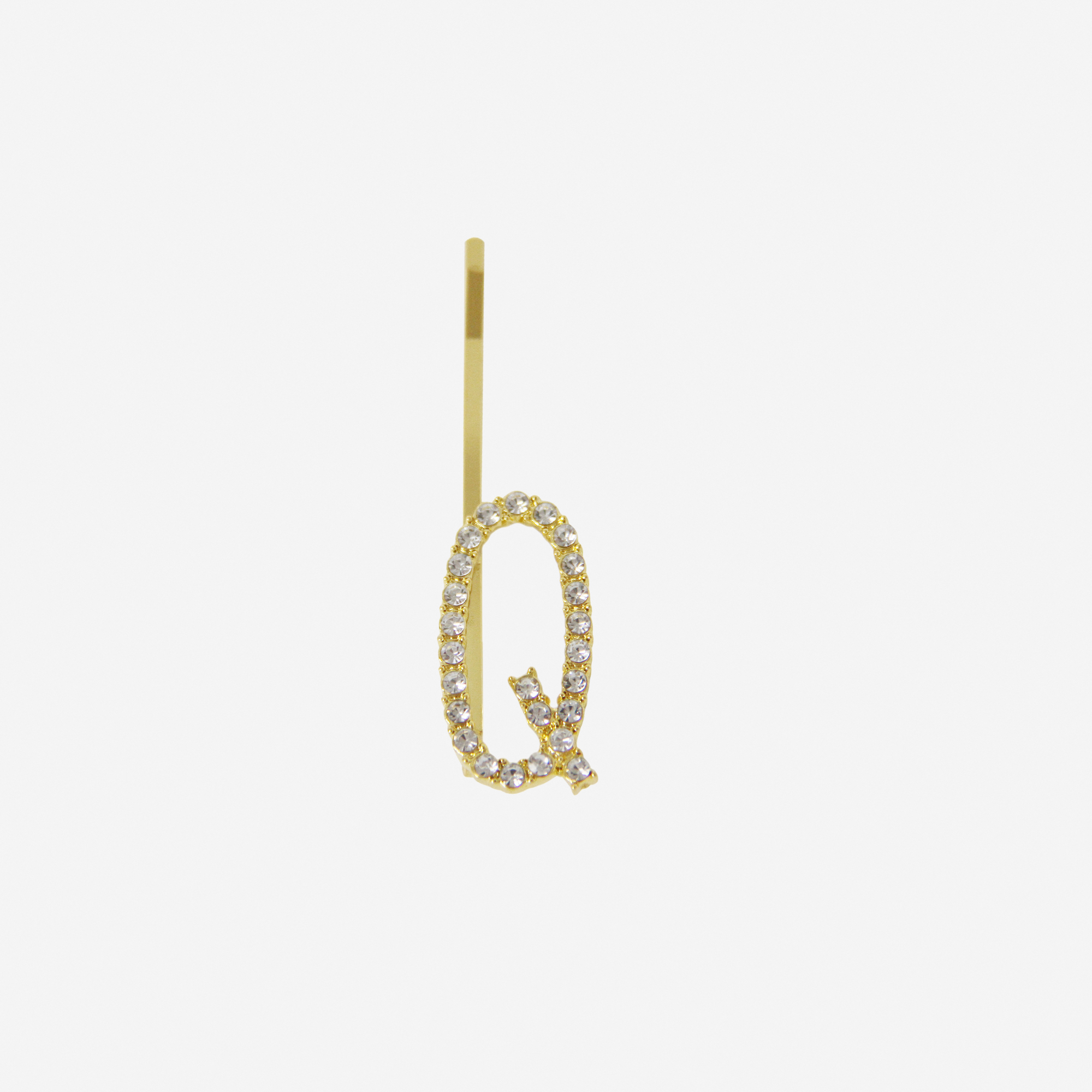Gold and crystal hair slide featuring the letter 'Q' on an off white background