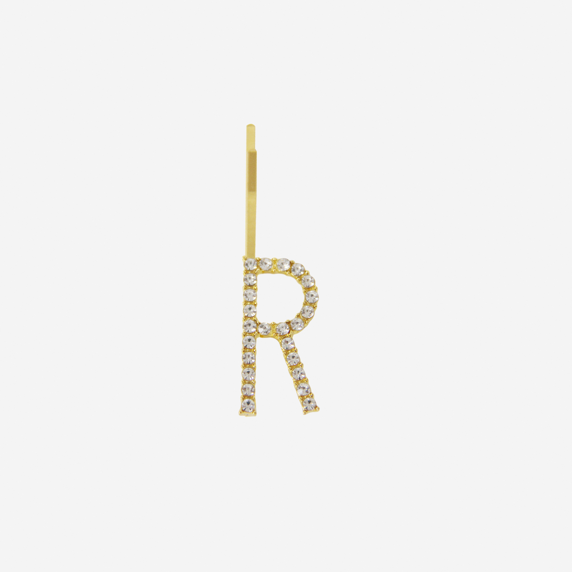 Gold and crystal hair slide featuring the letter 'R' on an off white background