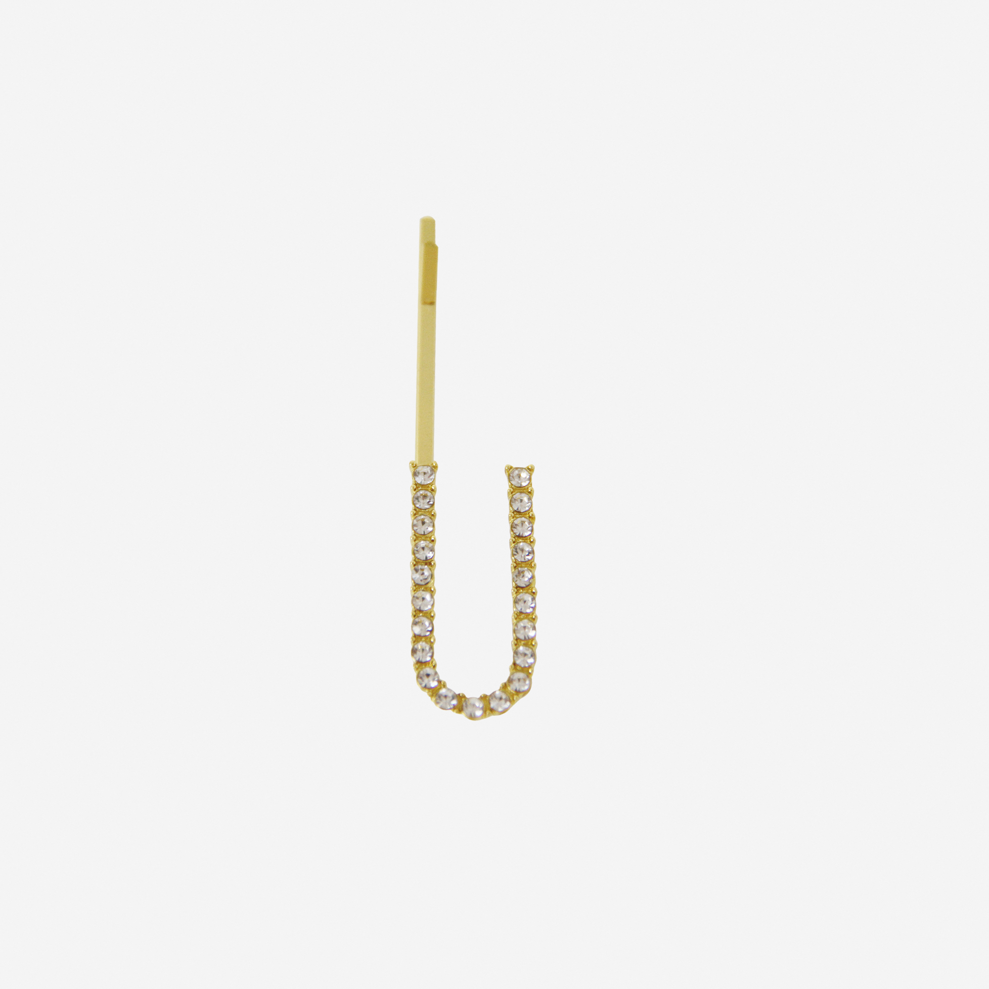 Gold and crystal hair slide featuring the letter 'U' on an off white background