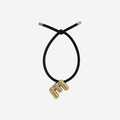 Black hair tie with gold letter 'E'  charm on an off white background