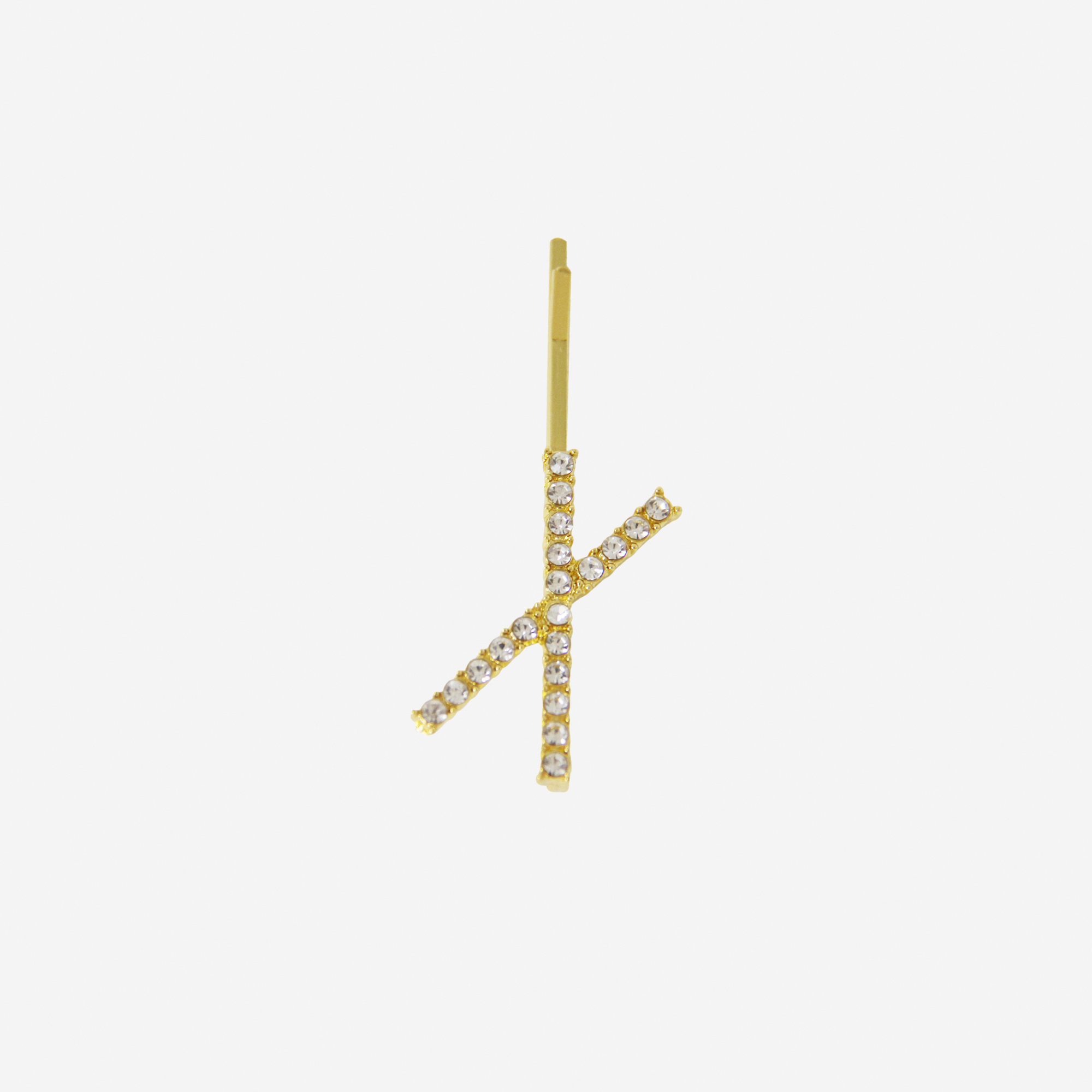 Gold and crystal hair slide featuring the letter 'X' on an off white background