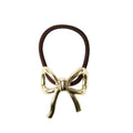 Gold bow-shaped hair tie on a white background
