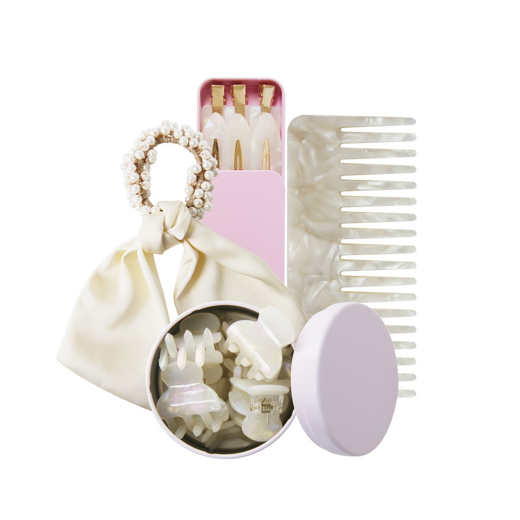 Set of hair accessories including a wide tooth resin comb, hair ties, and clips in a pink tin on a white background.