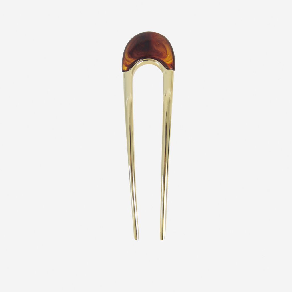 Gold hair pin with a brown resin detail on the top on an off white background