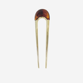 Gold hair pin with a brown resin detail on the top on an off white background
