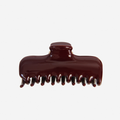 Large burgundy hair claw on an off white background