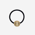Black hair elastic with a gold vintage inspired button, on an off white background