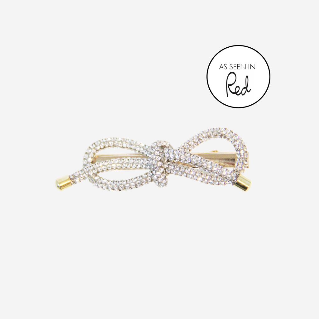 Crystl bow hair clip with an as seen in red magazine logo on an off white background
