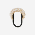 Gold crystal encrusted hair tie on an off white background
