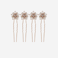 Set of 4 rose gold and crystal flower hair pins on an off white background