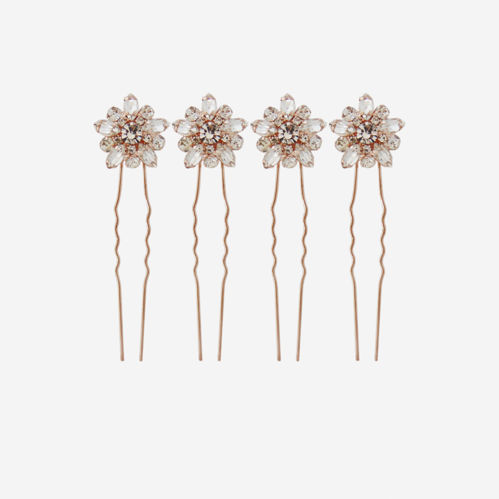 Set of 4 rose gold and crystal flower hair pins on an off white background