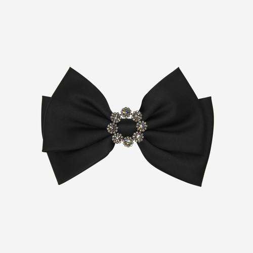 Black bow hair clip with a decorative crystal center on an off white background