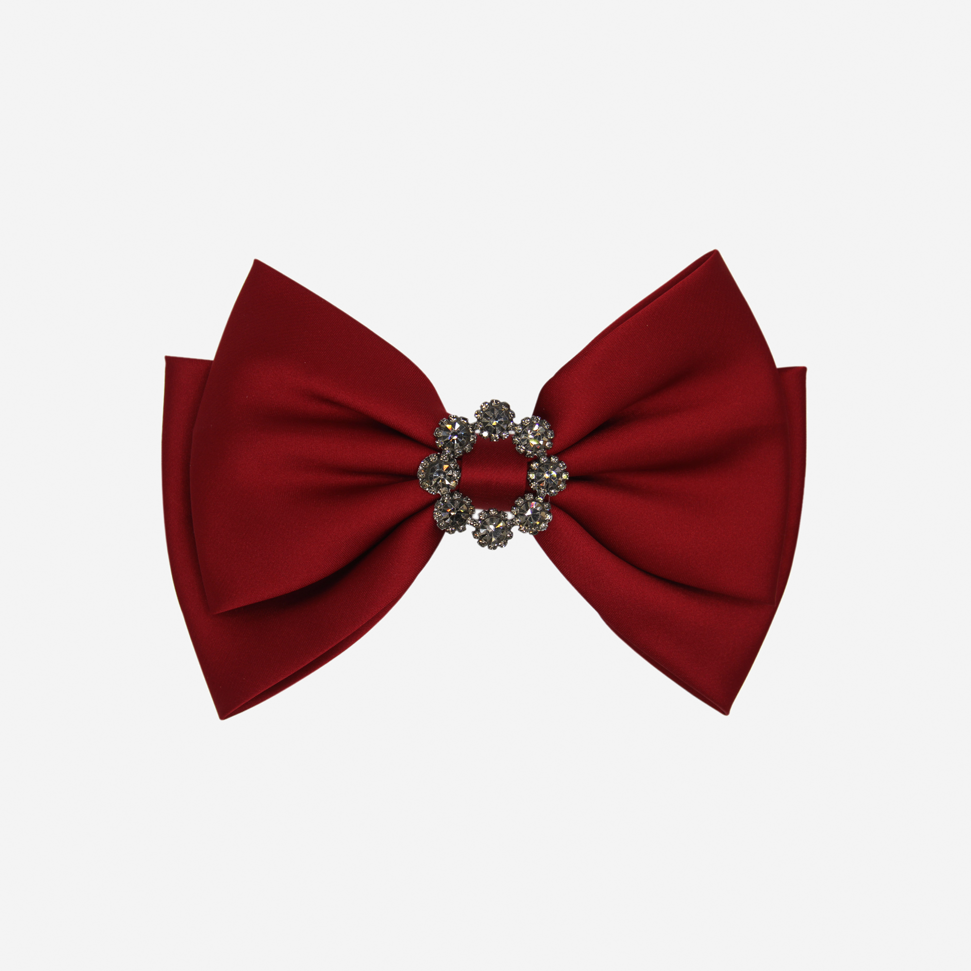 Red bow hair clip with a decorative crystal center on an off white background