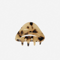 Light tortoiseshell medium sized hair claw with a cut away feature on an off white backgound