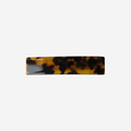 Dark tortoiseshell hair clip on an off white background