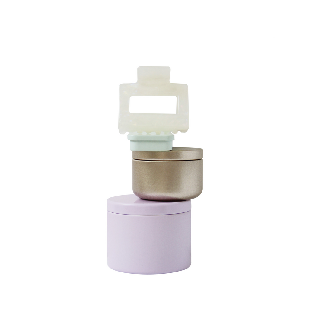 Braid & Bow gift set, stack of colourful tins containing hair claws, hair ties and kirby grips with a hair claw balanced on top, on a white background