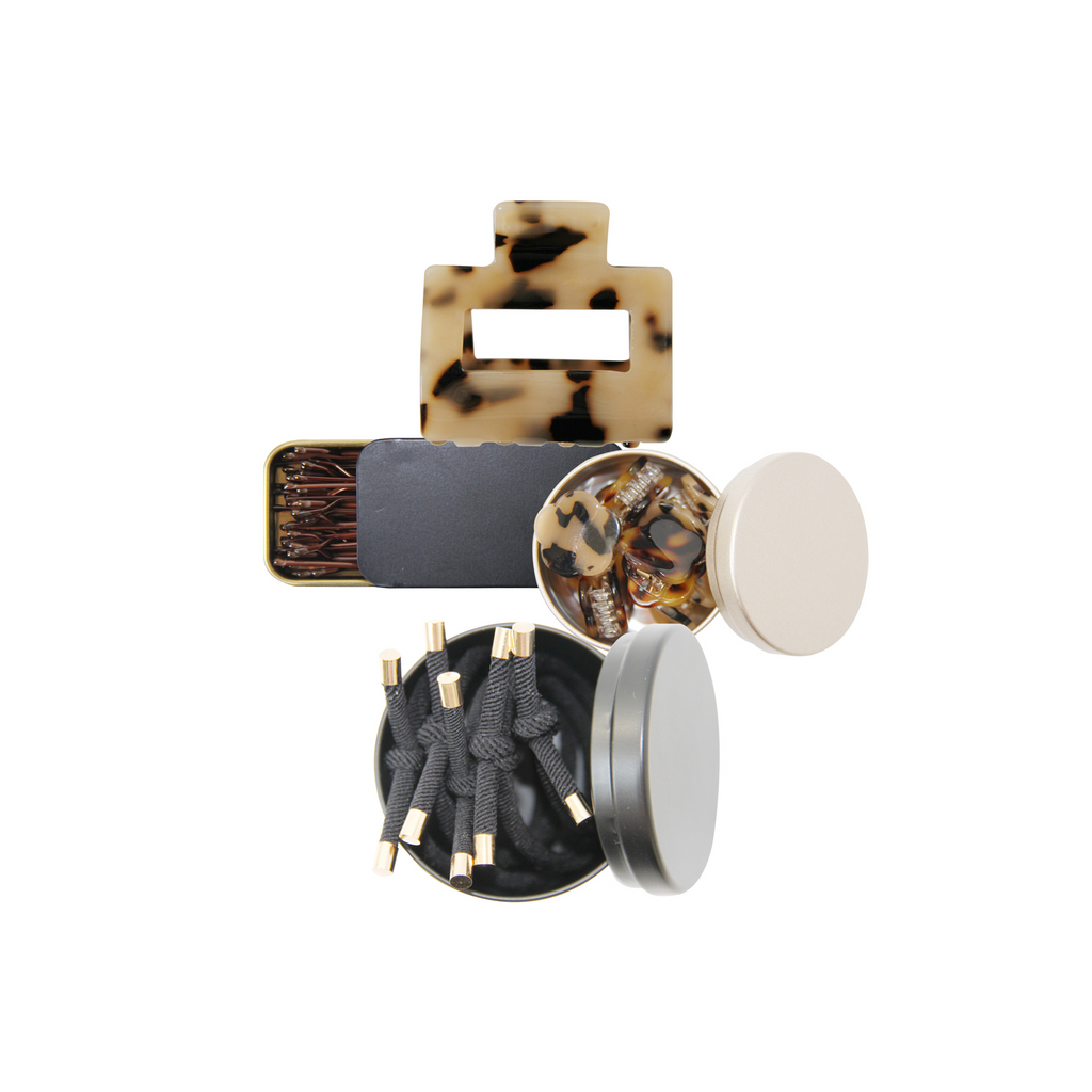 Set of hair accessories, showing hair ties, mini hair claws, kirby grips and a hair claw on a white background