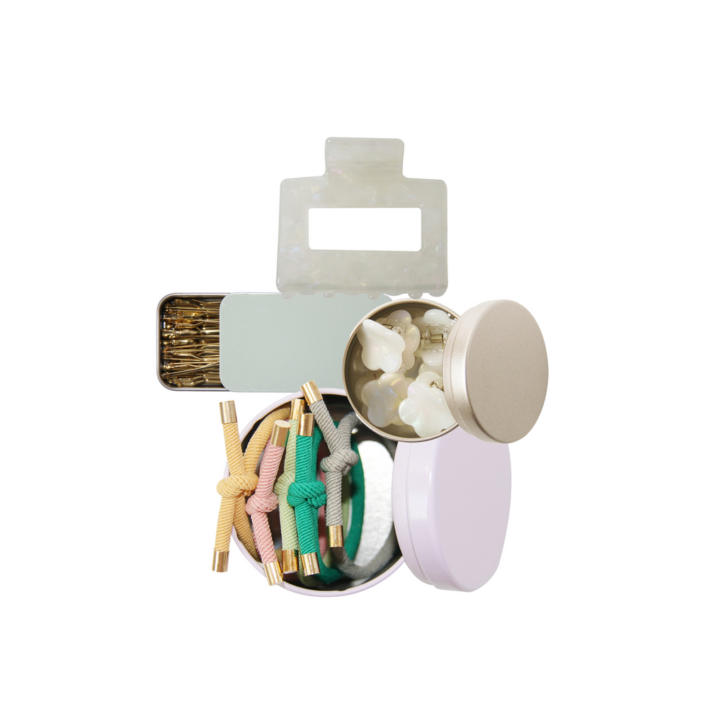 Set of hair accessories, showing hair ties, mini hair claws, kirby grips and a hair claw on a white background