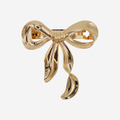 Statement gold bow hair barrette on an off white background