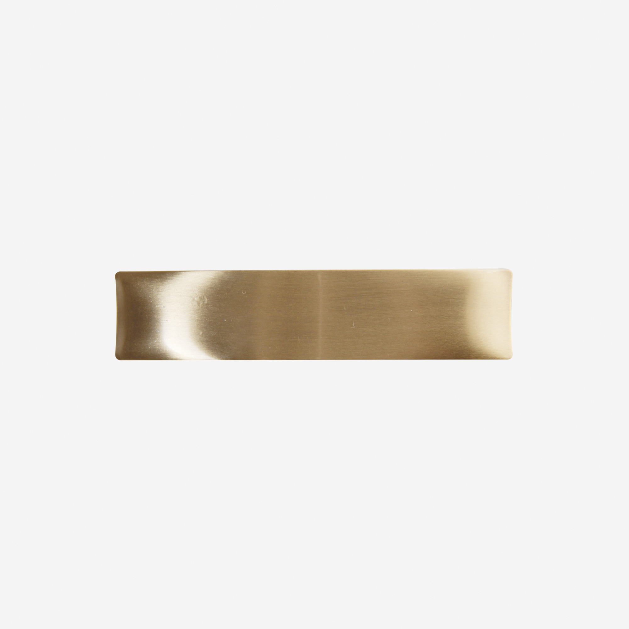 Matt gold hair clip on an off white background