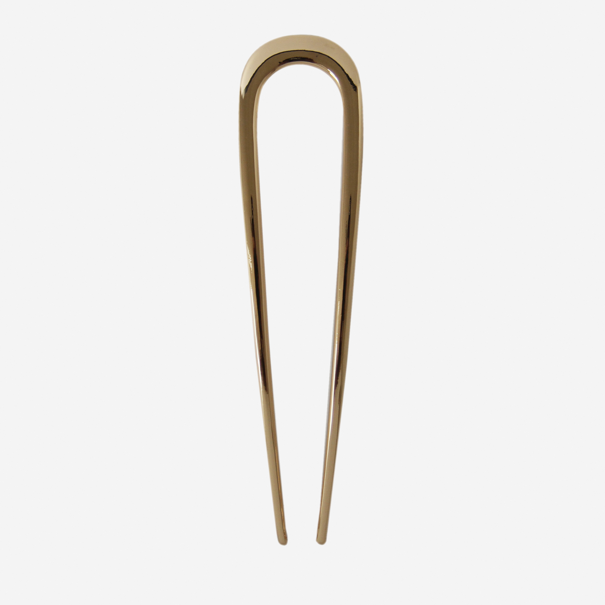 Gold metal french hair pin on an off white background