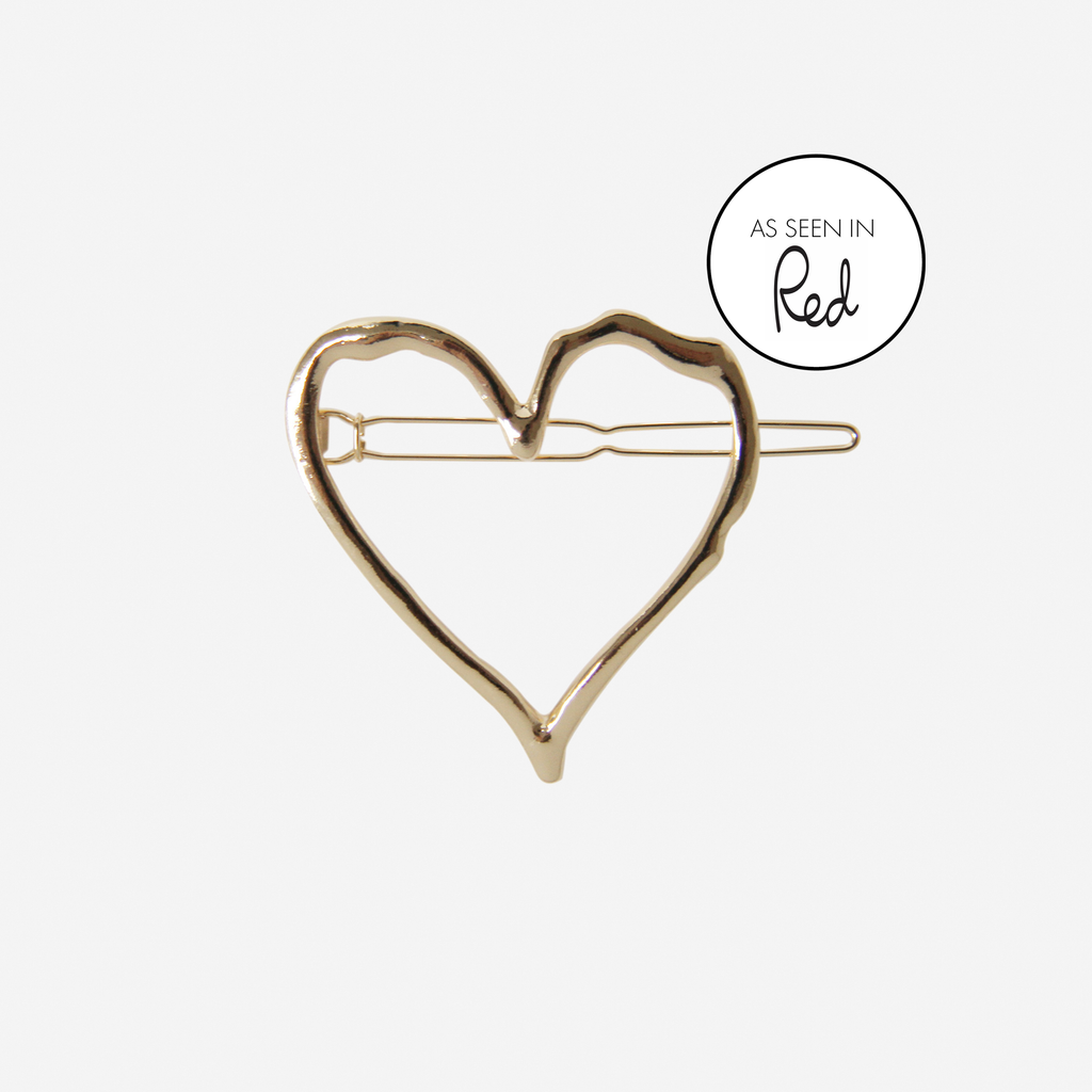 Gold heart hair clip with an as seen in Red magazine logo on an off white background