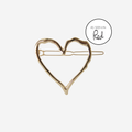 Gold heart hair clip with an as seen in Red magazine logo on an off white background