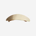 Oval gold slightly curved hair clip on an off white background