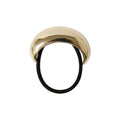Statement gold oval ponytail cuff on a black elastic hair tie on a white background