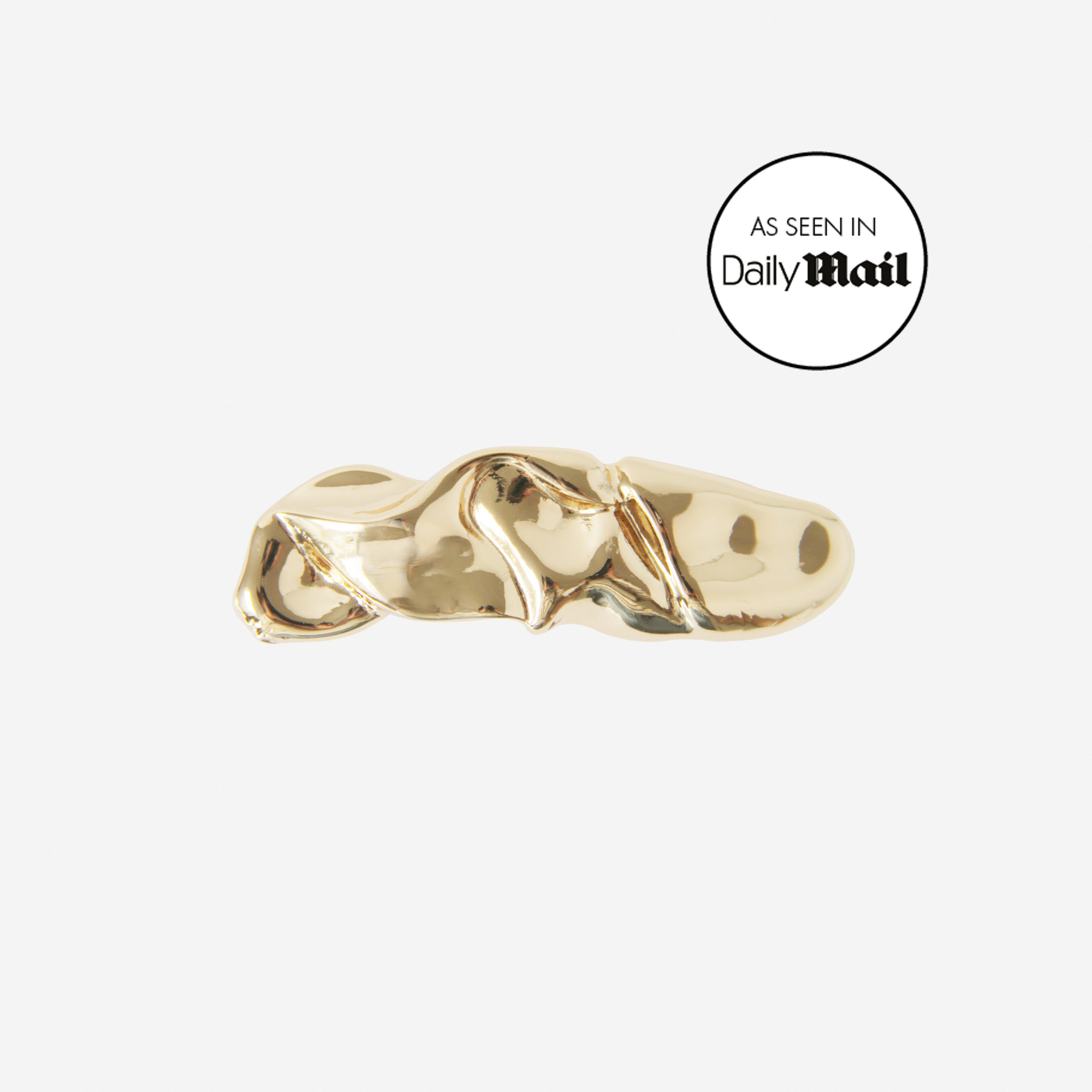Gold folded hair clip featuring an as seen in Daily Mail logo, on an off white background