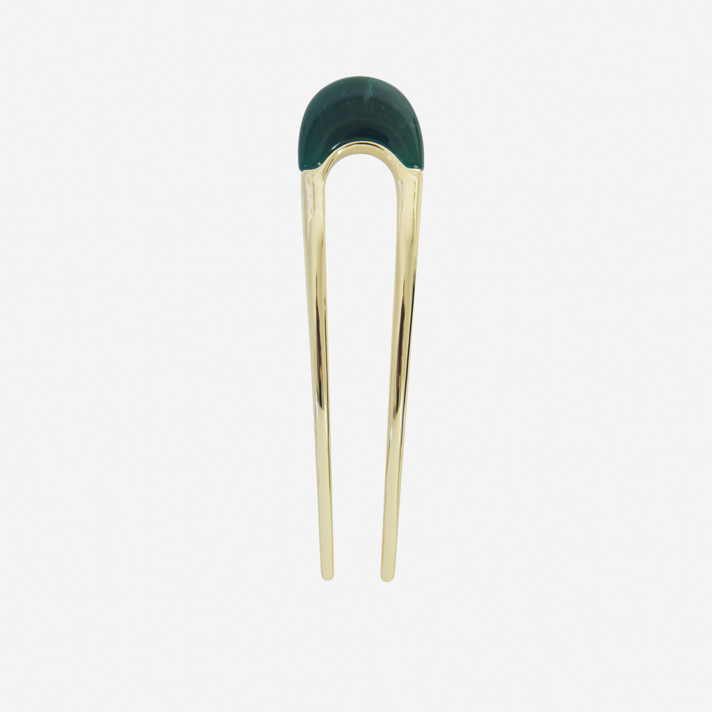 Gold hair pin with a green resin detail on the top on an off white background