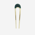 Gold hair pin with a green resin detail on the top on an off white background