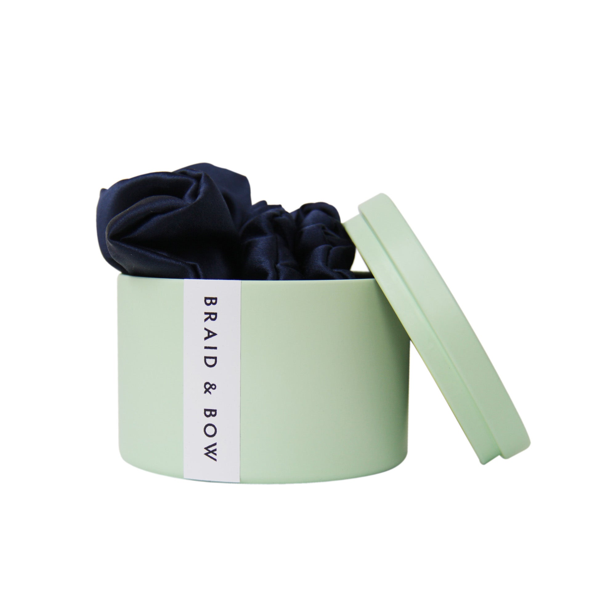 Green Braid & Bow tin with three navy blue silk scrunches on a white background