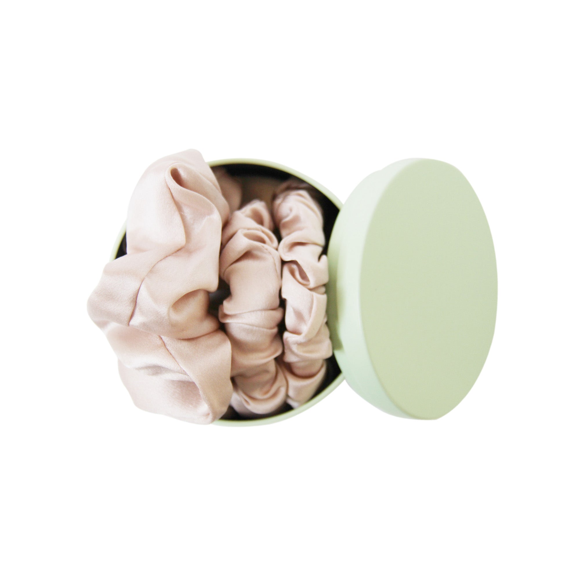 Green Braid & Bow tin with three blush silk scrunches on a white background