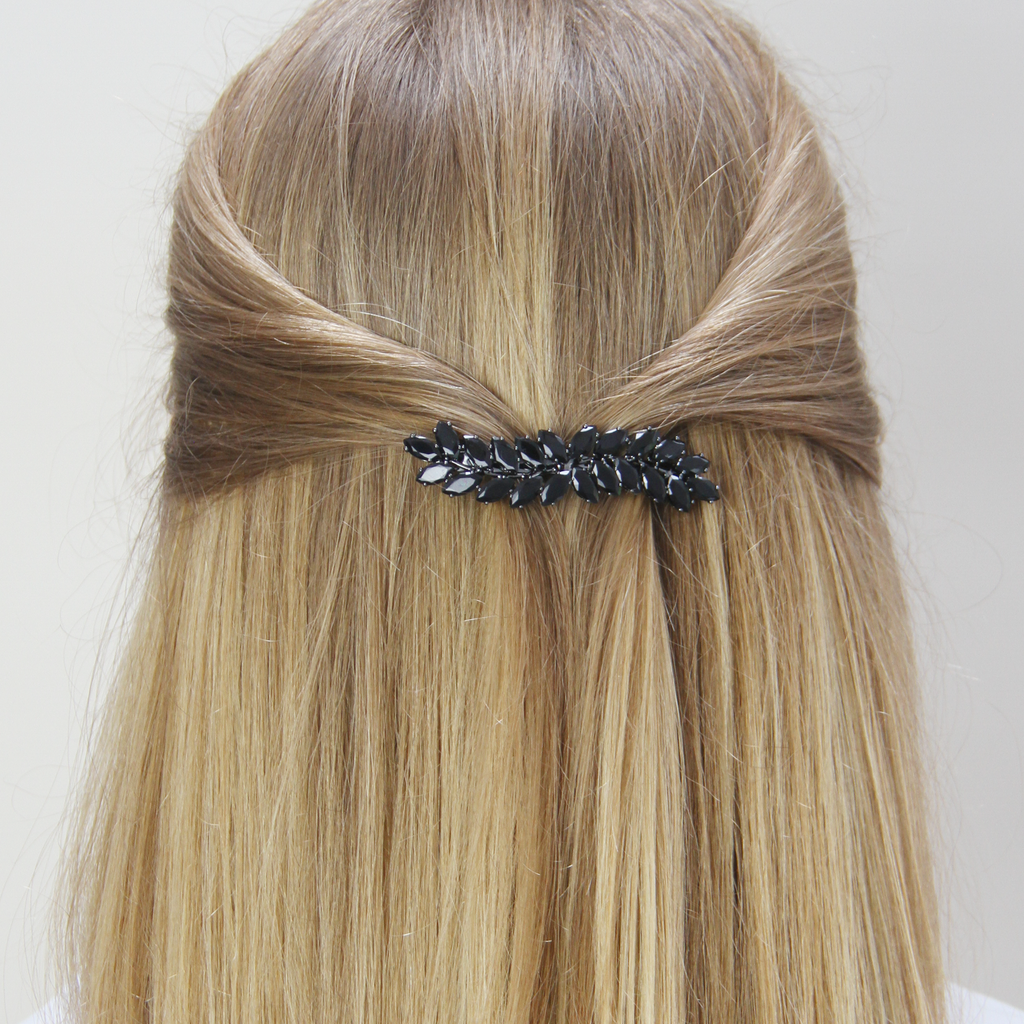 Blonde hair styled with in a half updo with a vintage inspired crystal black ivy decorative hair clip on a white background