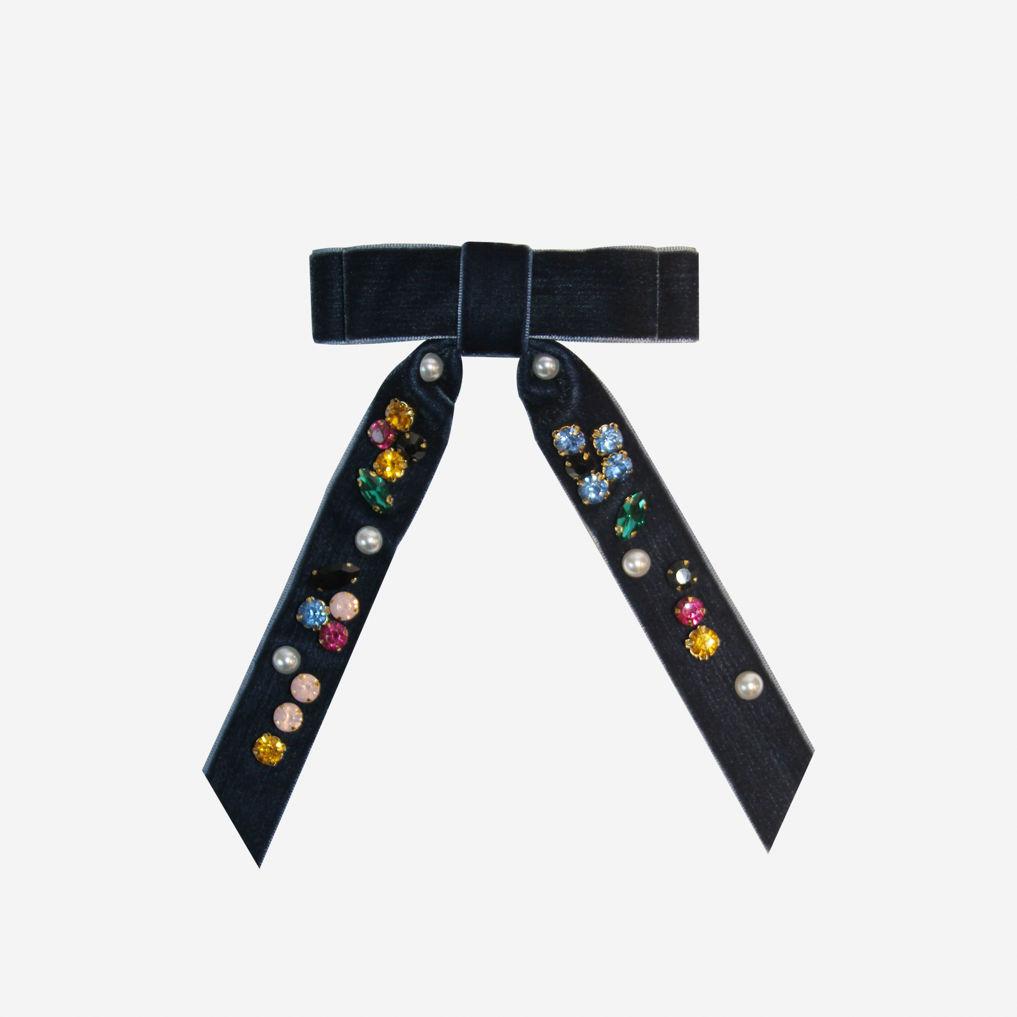 Navy blue velvet hair bow embellished with colourful jewels and pearls on an off white background