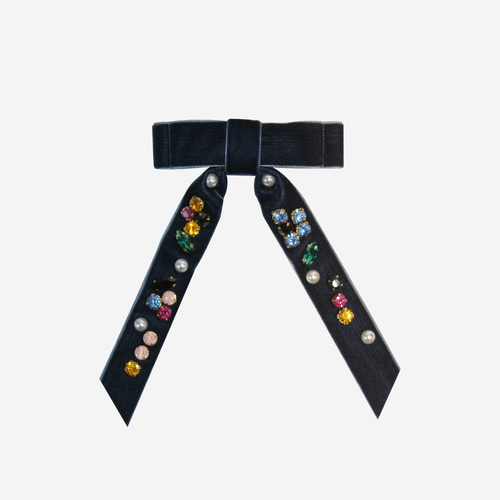 Navy blue velvet hair bow embellished with colourful jewels and pearls on an off white background