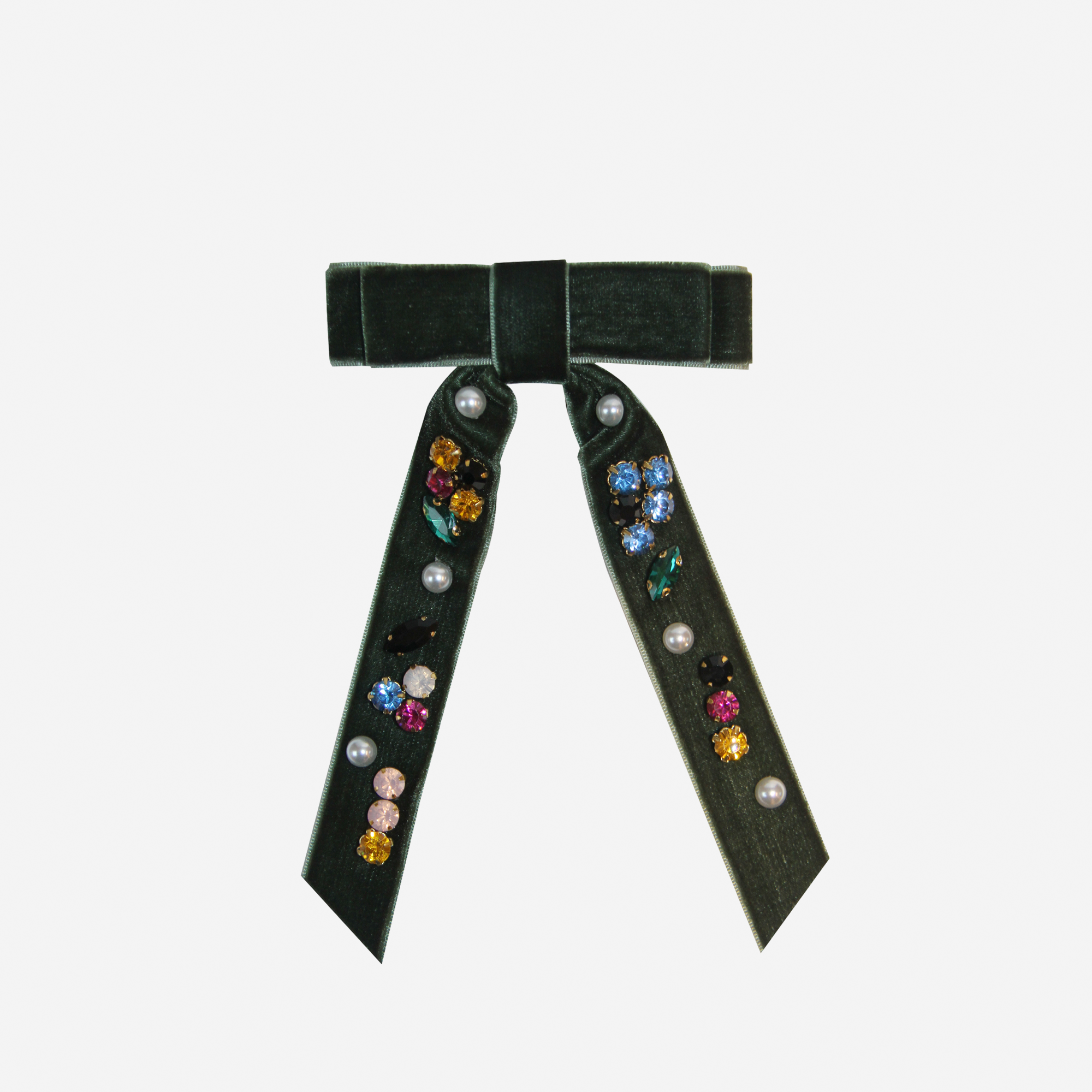 Green velvet hair bow embellished with colourful jewels and pearls on an off white background