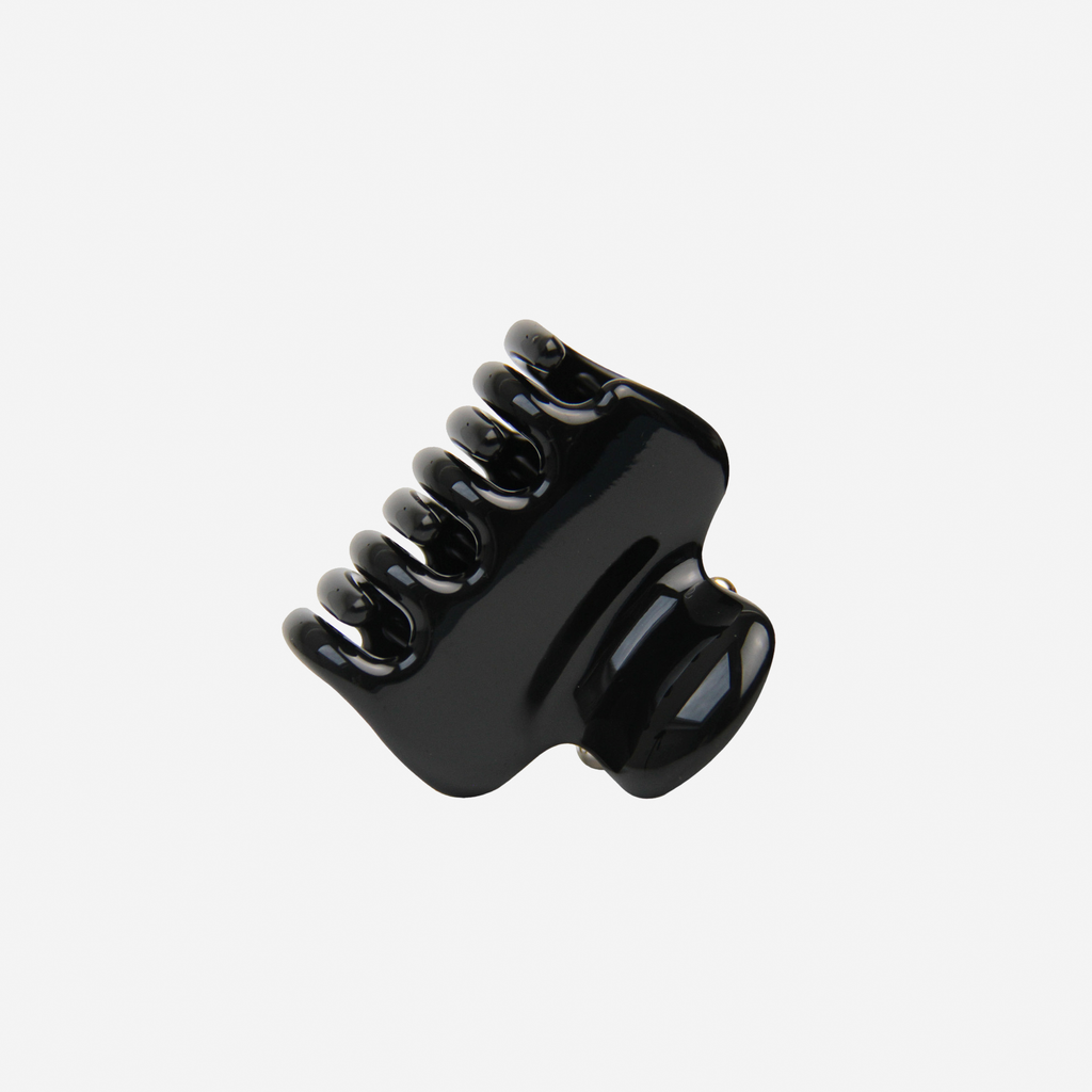 Medium black hair claw on an off white background