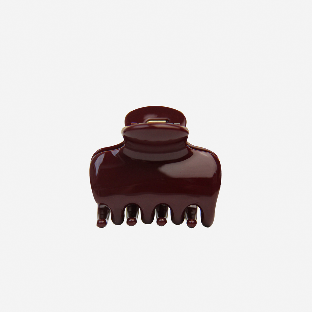 Medium burgundy hair claw on an off white background