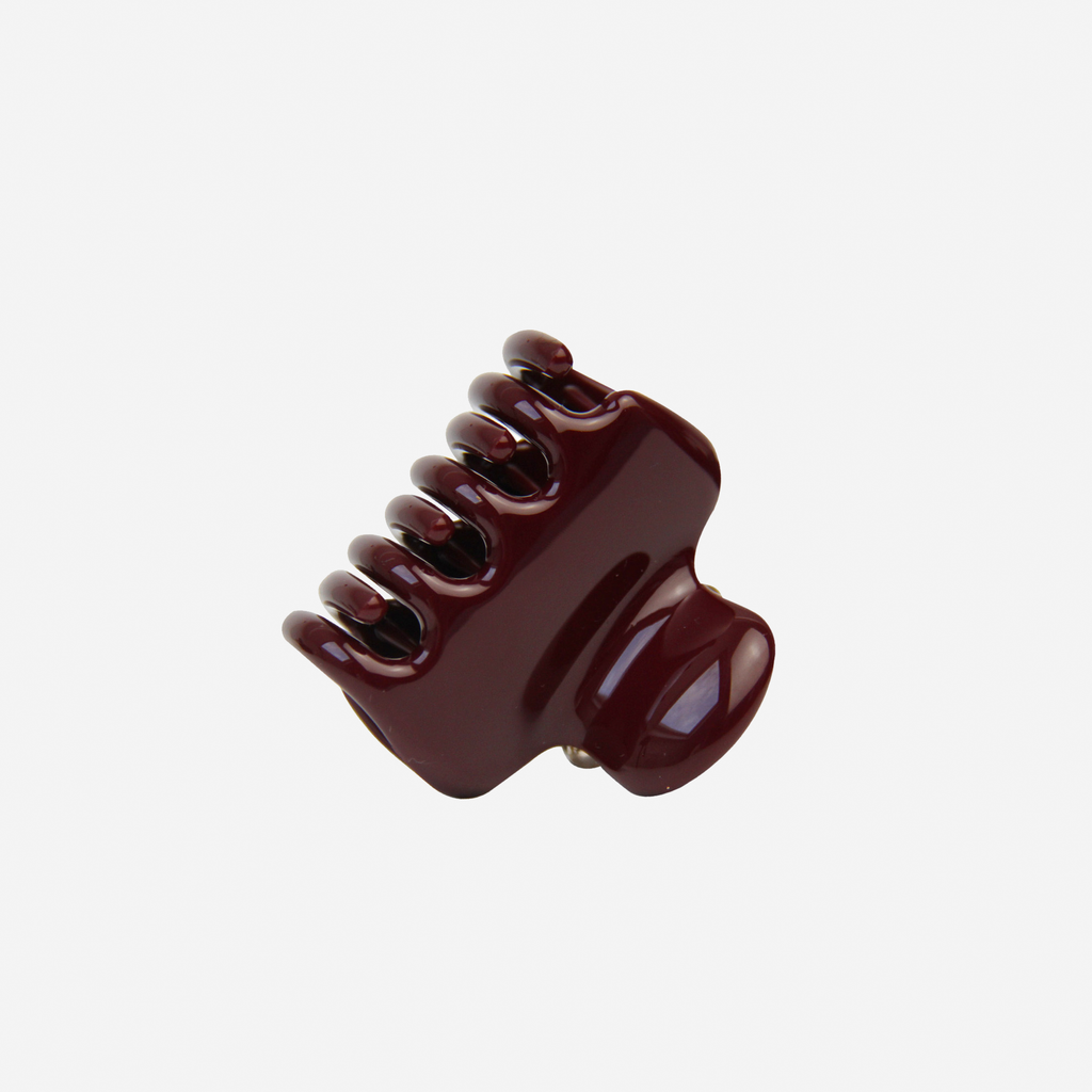 Medium burgundy hair claw on an off white background